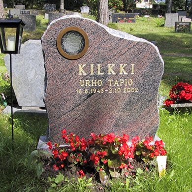 Punainen hautakivi pyöreällä kynttiläaukolla